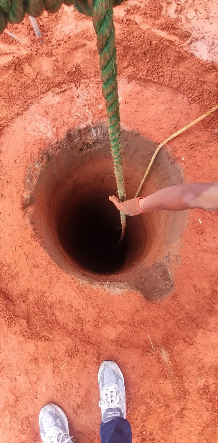 Volunteer lowering a rope into a hand-dug community well